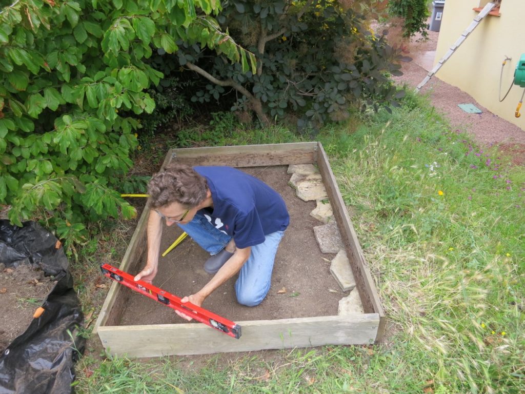 Pour que la réserve d'eau ait la même hauteur partout, il faut que le terrain soit bien de niveau. J'ai donc calé le cadre avec des dalles et remblayé l'un des côtés.