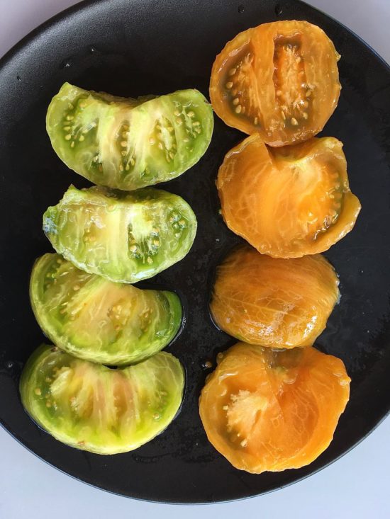 Deux tomates d'apparence extérieure très semblable (jaune strié de vert) mais dont l'intérieur est bien différent. À gauche : Malakhitovaya, à droite : Kozula